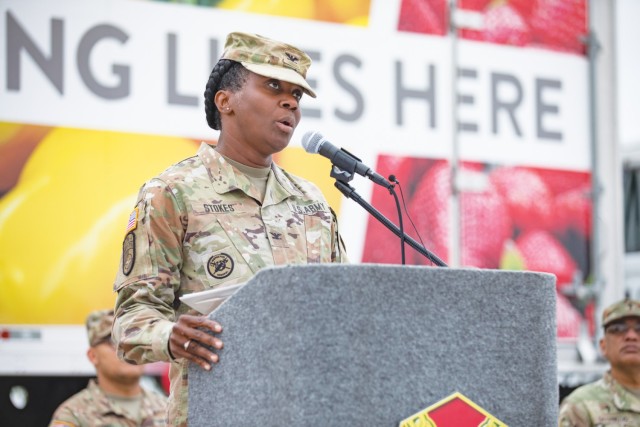 A woman standing speaks behind a podium.
