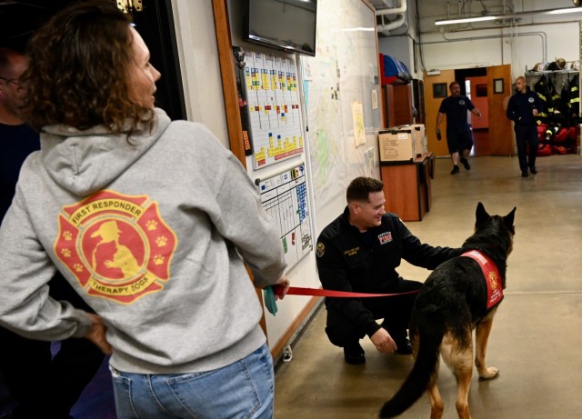 Kelly Nguyen, left, a volunteer with First Responder Therapy Dogs holds the leash of King, the dog, for deputy fire chief Travis Wondrash to pet during a visit at Fire Station 1, Presidio of Monterey,
