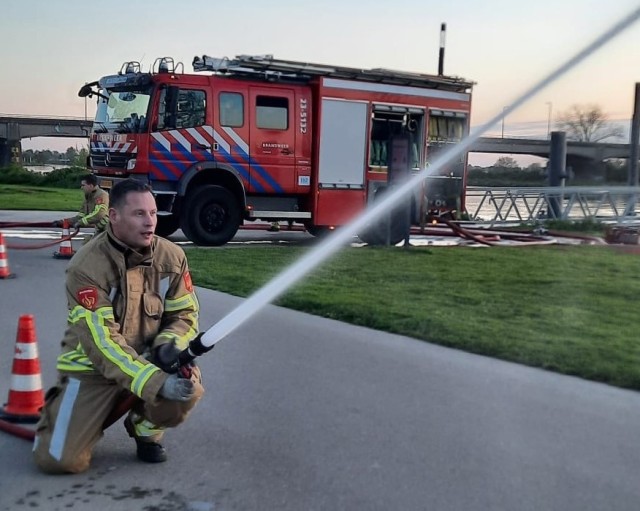 Firefighter sprays water out of fire truck hose.