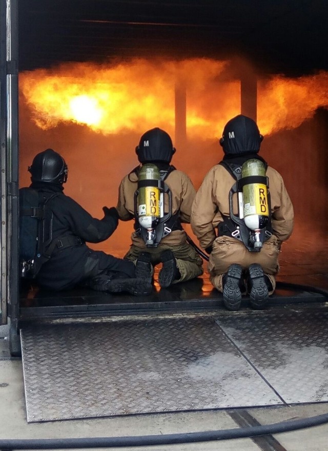 Three firefighters prepare to spray a flashover fire.