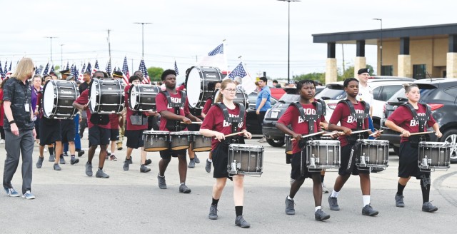 High school students march while playing different types of drums harnessed to their bodies.
