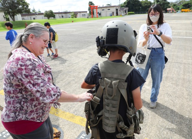 A resident from the Central Children’s Home tries on a pilot's tactical vest while touring a UH-60 Black Hawk helicopter at Camp Zama, Japan, Sept. 23, 2024. A group of children from the home saw the helicopter as part of their visit to the...