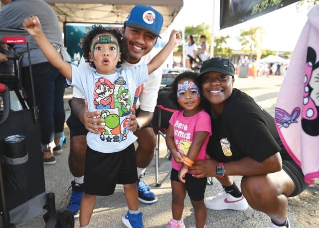 A husband and wife and their two kids pose for a picture, with the parents squatting and the kids standing in front of them.