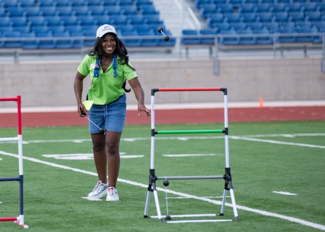 A woman watches as a string with two balls attached to the ends flies in the air toward a short, standing ladder.