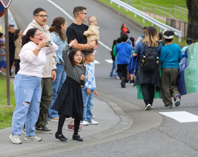 The Rosales family, foreground, watch a homecoming parade at Camp Zama, Japan, Oct. 10, 2024. Several U.S. Army Garrison Japan personnel helped with the parade and a bonfire that night in support of Zama Middle High School students.