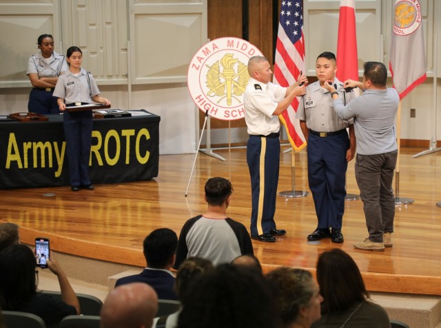 Cadet Aidan Chiong, right, is promoted to sergeant during a Junior Reserve Officers’ Training Corps recognition ceremony at Camp Zama, Japan, Oct. 17, 2024. About 40 cadets were honored with awards and promotions during the ceremony.