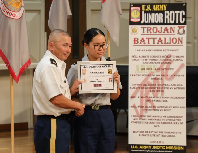 Retired Sgt. Maj. Danny Davis, left, the Junior Reserve Officers’ Training Corps program’s Army instructor, presents an award certificate to Cadet Laura Larm for her efforts in the homecoming parade during a recognition ceremony at Camp Zama,...
