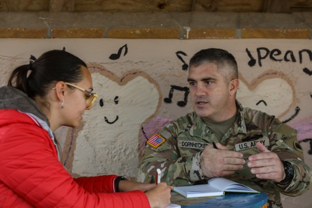 U.S. Sgt. 1st Class Lonnie Dornhecker, assigned to the Oregon Army National Guard, goes into a Kosovo community and speaks with civilian role-player, Milica Jovanovic, to gather information that assists KFOR in predicting flash point events that...