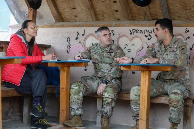 U.S. Sgt. 1st Class Lonnie Dornhecker and Sgt. Kaleb Wood, assigned to the Oregon Army National Guard, go into a Kosovo community and speak with civilian role-player, Milica Jovanovic, to gather information that assists KFOR in predicting flash...