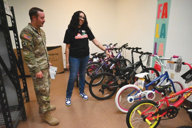 Two people, a man and a woman, standing look at a row of bicycles in a room.