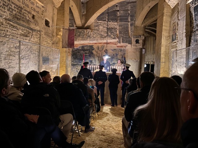 People sit and watch as Christmas Eve service is underway in the cave