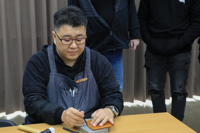 Hwang, Chan-oh, a leatherworking artisan, carefully creates perforated holes on a cowhide leather wallet during a Newcomers Cultural Awareness and Immersion Tour hosted by Dongducheon city, Bosan-dong Community Center, Bosan-dong, South Korea,...