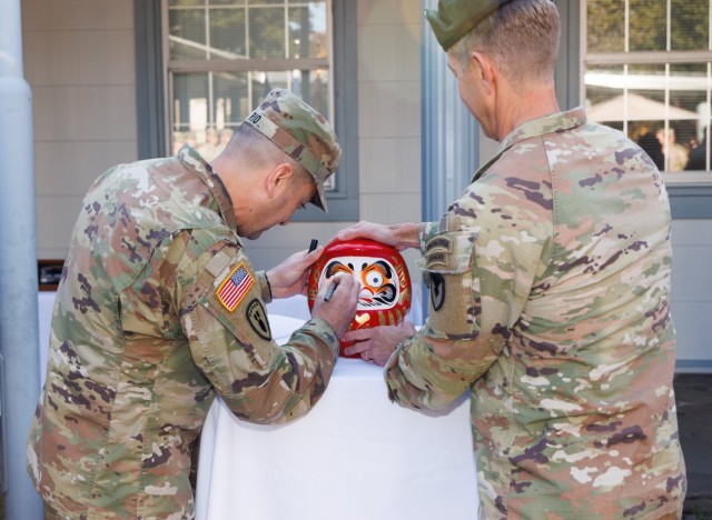 Col. Marcus Hunter, right, commander of U.S. Army Garrison Japan, watches Command Sgt. Maj. David A. Rio paint in the second eye of his "daruma" doll before a change of responsibility ceremony at Camp Zama, Japan, Dec. 12, 2024. Command...