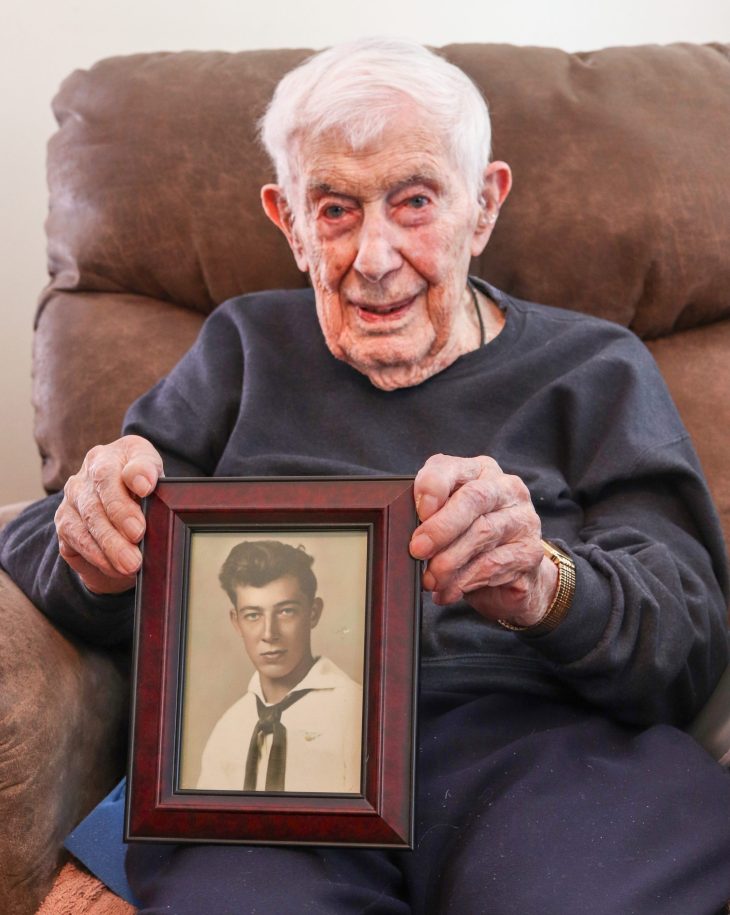 Emerson Pell, holding a framed photo of himself in uniform. 