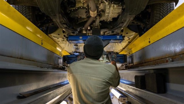 An inspector checks the under carriage of a vehicle.