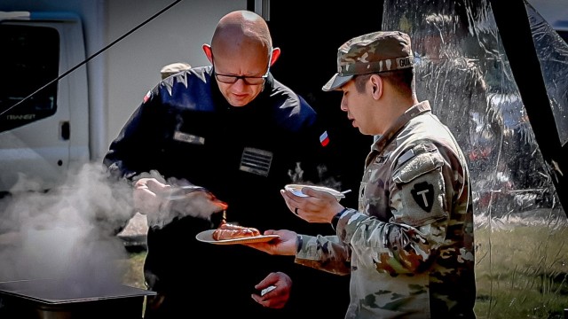 A Polish Soldier serves grilled kielbasa and pork neck to a U.S. Soldier following a joint emergency services exercise in Powidz, Poland, May 15, 2024. Coordinators from the 33rd Air Base invited U.S. participants to join them for a cookout after...