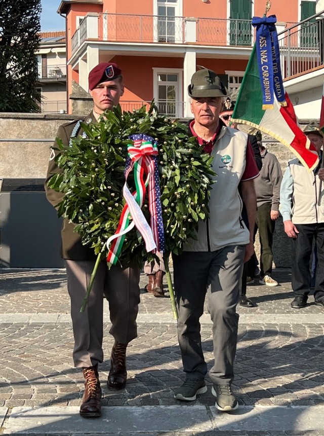 Pfc. Donovan Jourdan, 23, of Denver, Colorado assists an Italian Alpini veteran to present a wreaths at a monument for 10th Mountain Division Soldiers killed during World War II near Torbole.