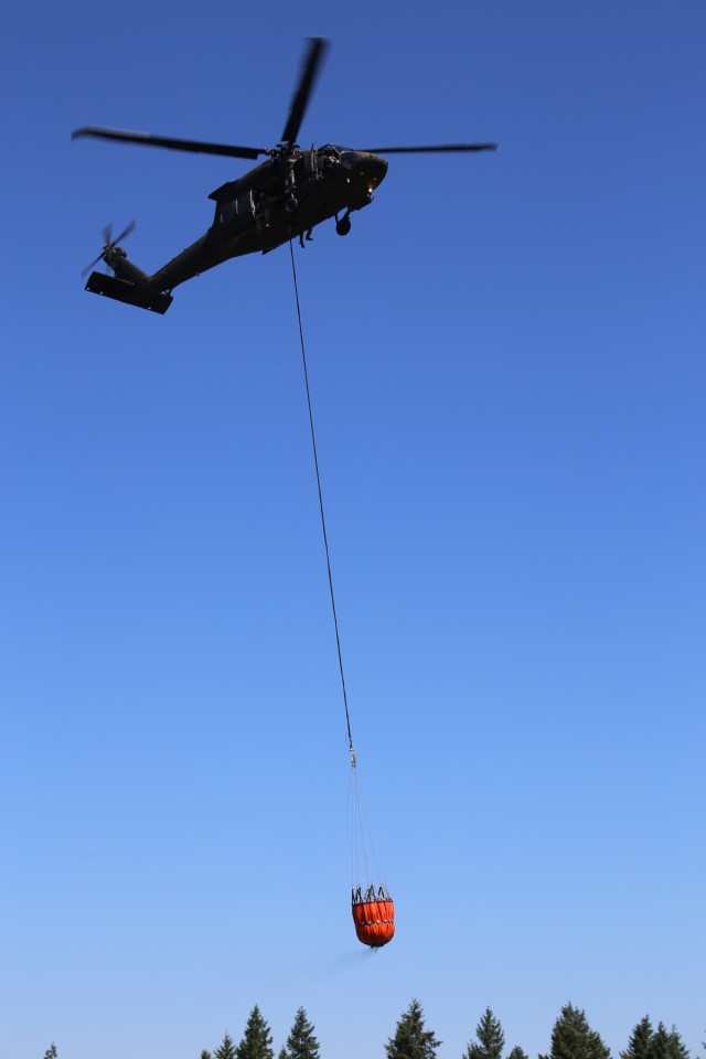 A UH-60 Blackhawk Helicopter from Charlie Company, 1st Battalion, 140th Aviation, 96th Troop Command, Washington Army National Guard conducts water bucket training with Central Pierce Fire and Rescue, June 30, 2025, near Puyallup, Wash.