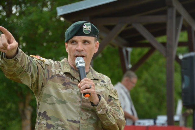 A U.S. Army colonel speaks on a microphone while pointing.
