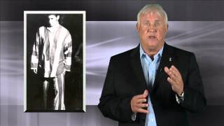 Man in suit jacket against a gray wall, with a older photo of him as a POW beside him.