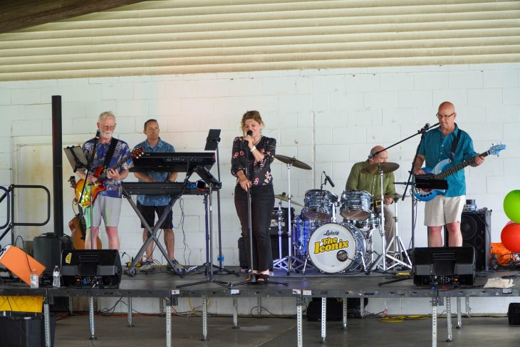 A band on stage playing music while a woman sings.
