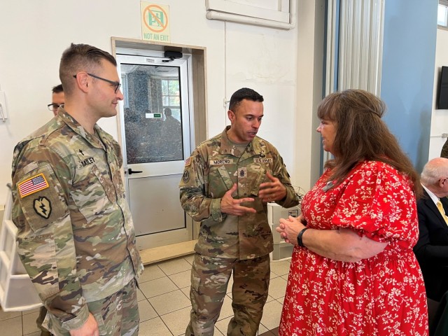 Command Sergeant Major Ricardo Moreno, The US Army Garrison Italy Command Sergeant Major discusses the centerpiece quilt with Terry Sim and Chaplain Maj. Brian Bailey at the Caserma Ederle Chapel on July 29, 2025 during the anniversary celebration...